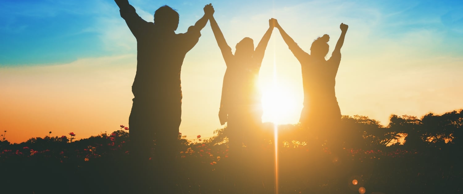 Silhouette of victorious team raising their hands in celebration of their achievement