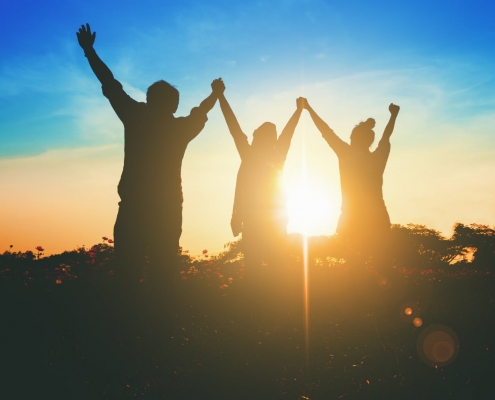 Silhouette of victorious team raising their hands in celebration of their achievement