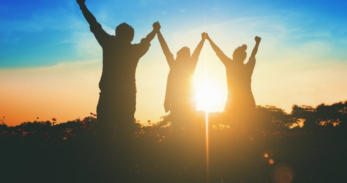 Silhouette of victorious team raising their hands in celebration of their achievement