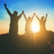 Silhouette of victorious team raising their hands in celebration of their achievement