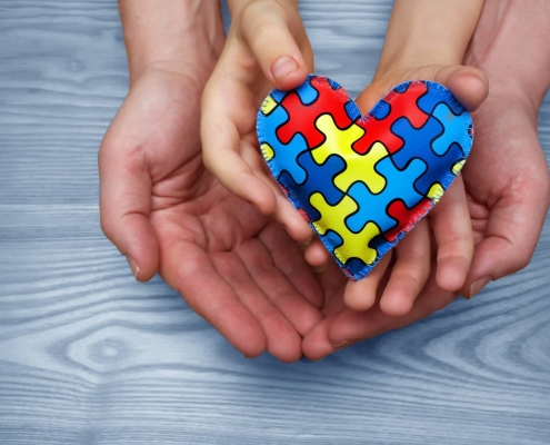 Heart puzzle symbol of autism in human hands