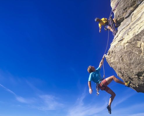 Two rock climbers scale a challenging peak