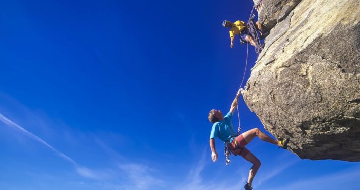 Two rock climbers scale a challenging peak