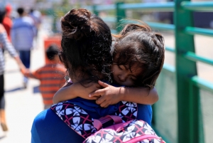 A young migrant child carried by her caretaker