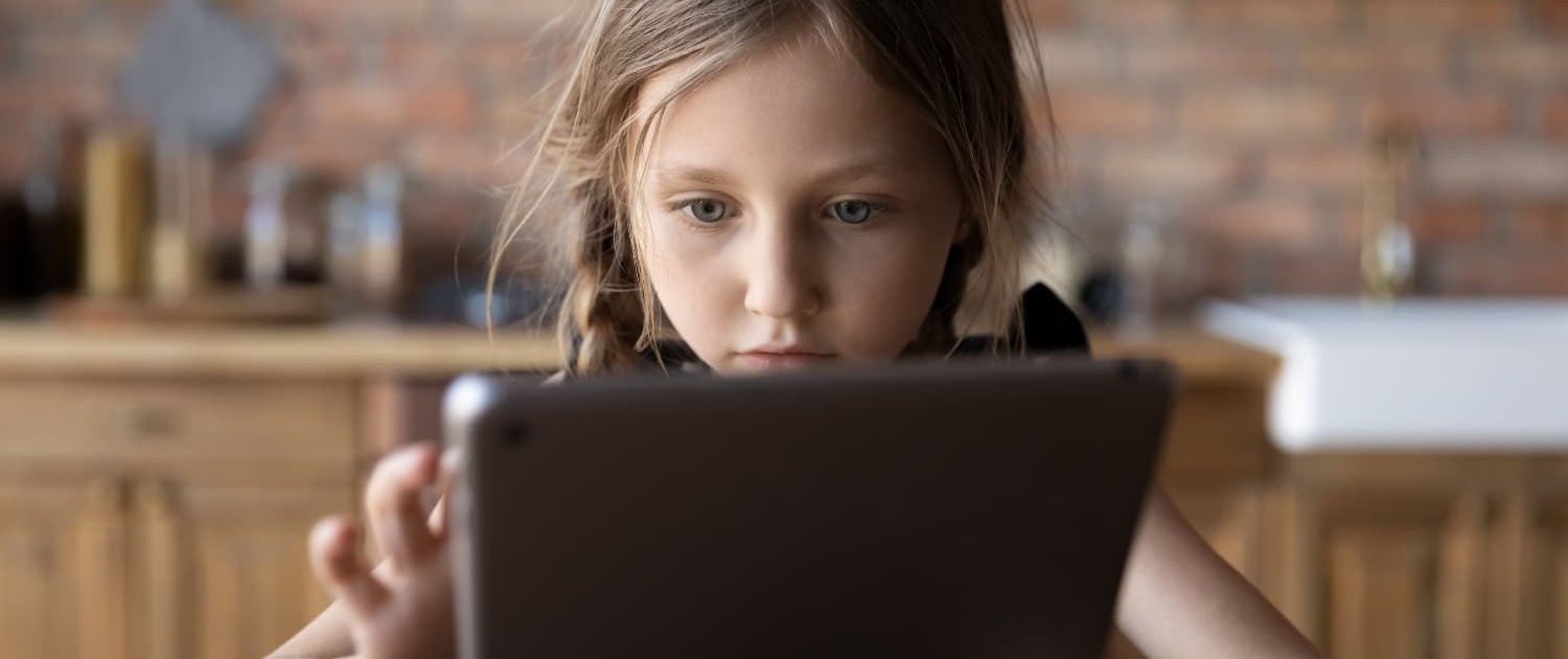 A young girl is focused on her tablet device