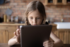 A young girl is focused on her tablet device