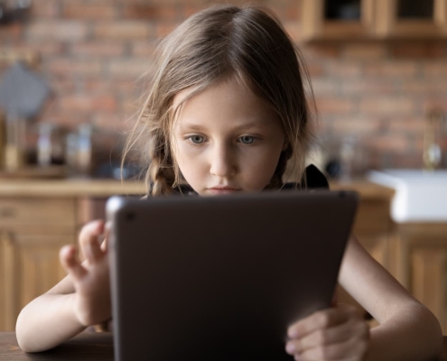 A young girl is focused on her tablet device