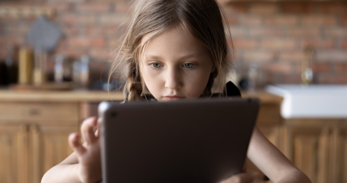 A young girl is focused on her tablet device