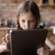 A young girl is focused on her tablet device