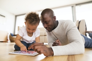 A parent and his toddler explore a digital tablet