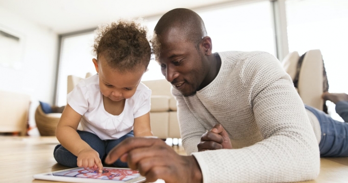 A parent and his toddler explore a digital tablet