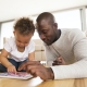 A parent and his toddler explore a digital tablet