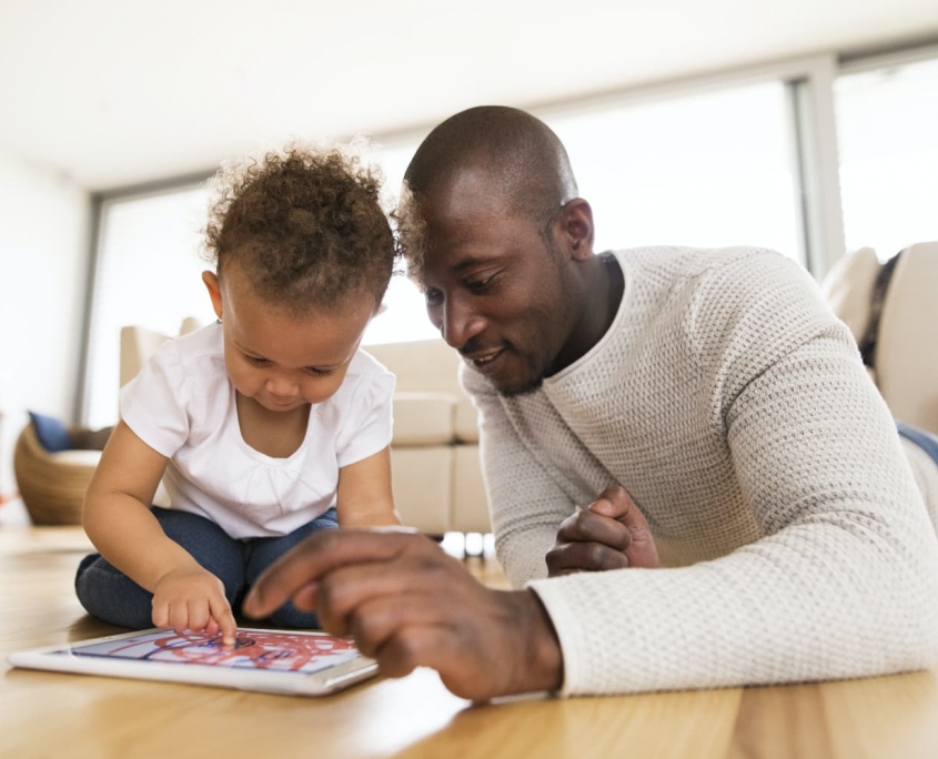 A parent and his toddler explore a digital tablet