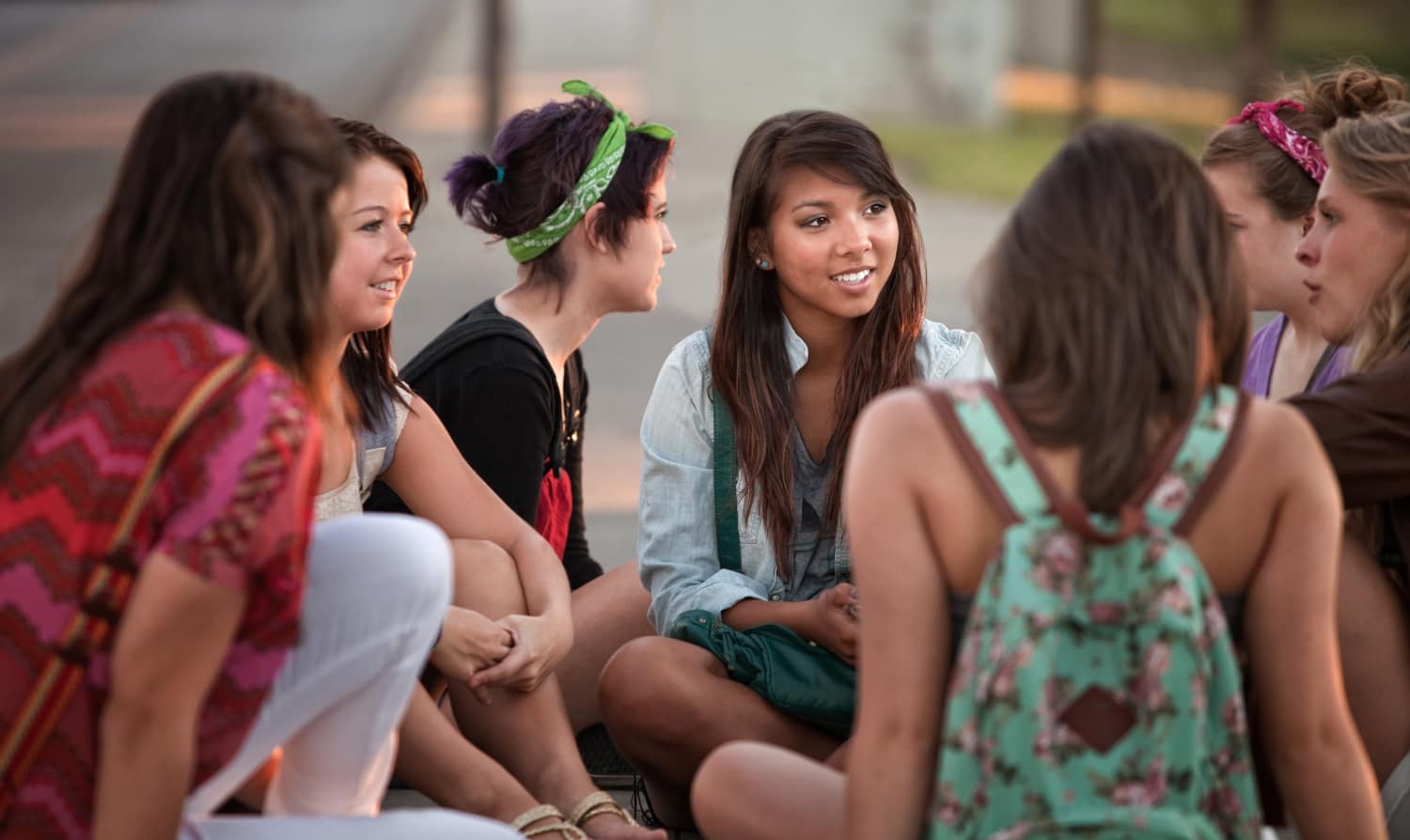 A group of teen girls sit talking with each other in a supportive manner