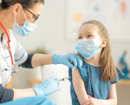 A female nurse gives a shot to a young girl