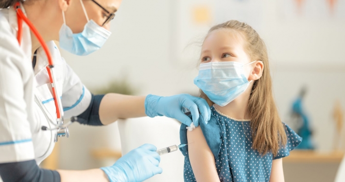 A female nurse gives a shot to a young girl