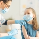 A female nurse gives a shot to a young girl