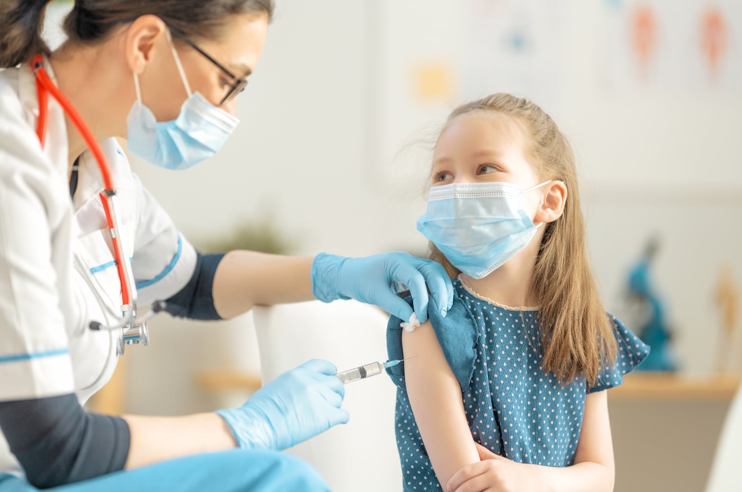 A female nurse gives a shot to a young girl