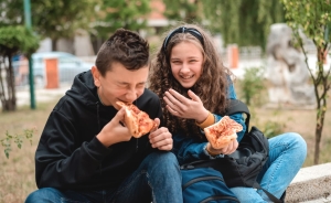 Teen girl laughing with a friend while they eat