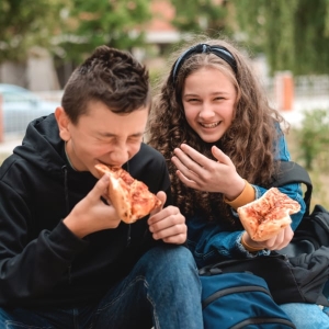 Teen girl laughing with a friend while they eat